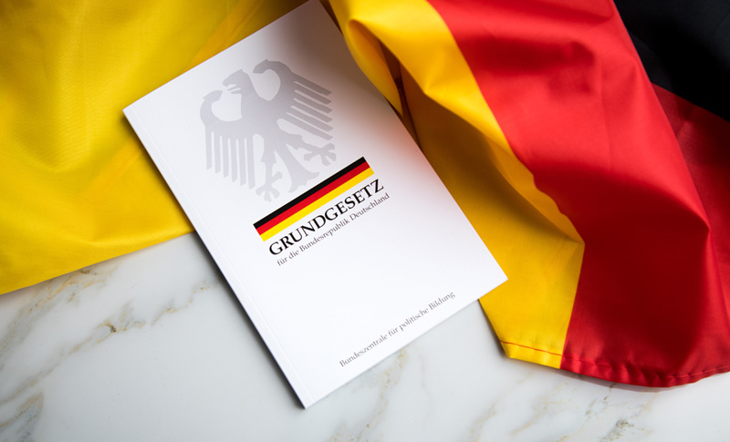 Grundgesetz Buch der Bundesrepublik Deutschland auf Flagge. Foto: Adobe Stock | Christin Klose